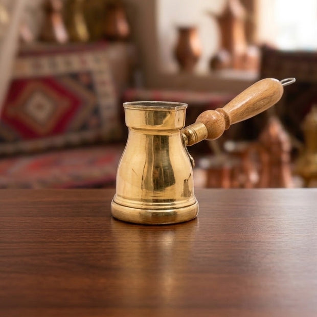 Golden copper cezve with a beige wooden handle